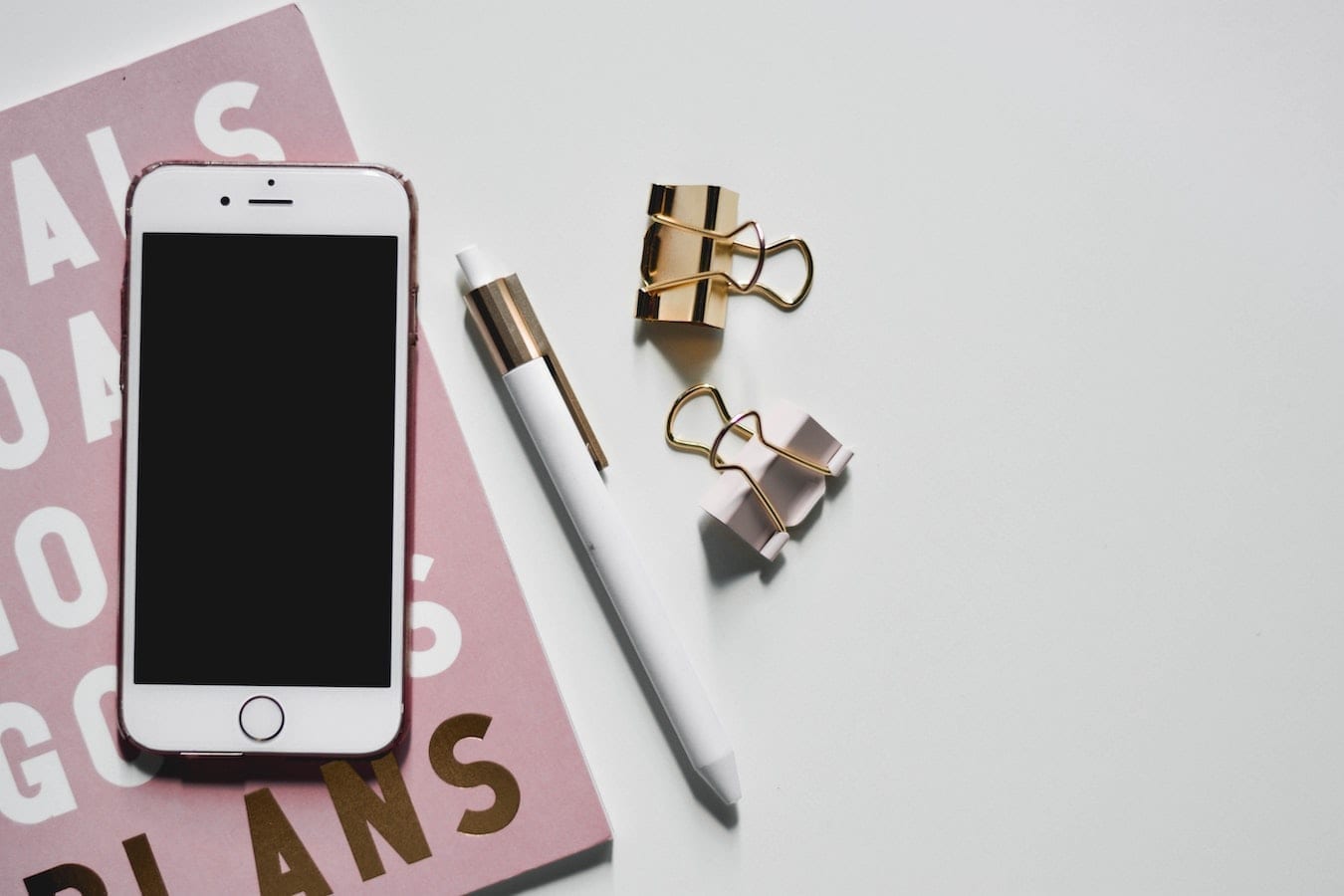 Photo d'un journal, un téléphone, un crayon et des pinces de bureau